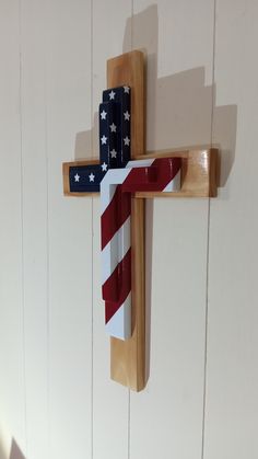 a wooden cross with an american flag painted on it's side hanging from the wall