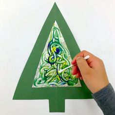 someone is painting a christmas tree with green and white paint on the bottom half of it