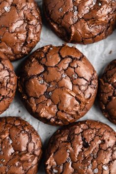 chocolate cookies are sitting on a piece of parchment paper