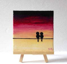 two birds sitting on top of a wooden easel