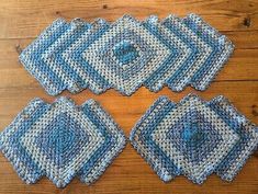 four blue crocheted placemats on a wooden table