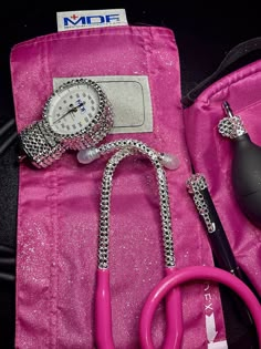 a pink bag with a stethoscope, watch and other items on it