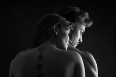 black and white photograph of two women with chinese writing on their upper back, looking at each other