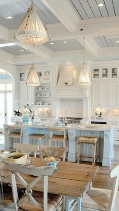 a kitchen filled with lots of white appliances and wooden tables surrounded by chairs in front of an island