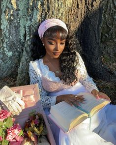 a woman sitting under a tree reading a book