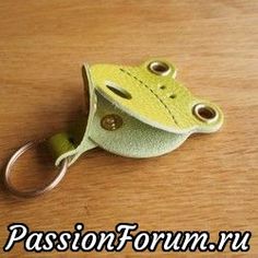 a green frog keychain sitting on top of a wooden table