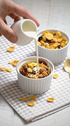 someone pouring milk into two bowls of cereal