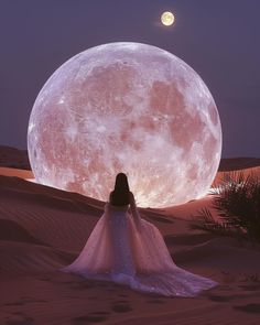 a woman is standing in the desert with her back to the camera, looking at the moon