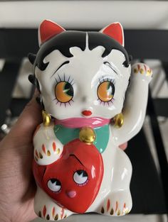 a white cat figurine holding a red heart