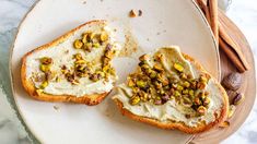 two pieces of bread with white frosting and nuts on top sitting on a plate