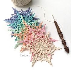 a crocheted star next to a ball of yarn and a knitting needle on a white surface