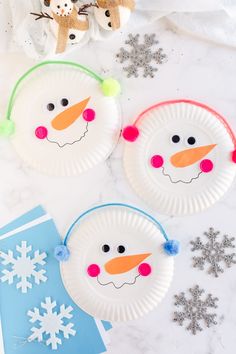 three paper plates with snowman faces on them and some decorations around the edges for decoration