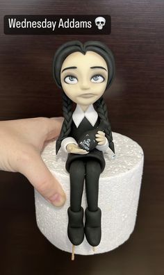 someone is holding a doll sitting on top of a toilet paper roll with the caption wednesday addams