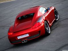 a red sports car driving on a track with its hood up and tail lights down