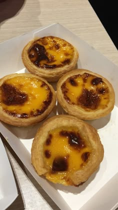 four mini cheese pies sitting on top of a white plate