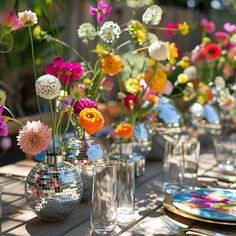 a table topped with lots of vases filled with different types of flowers next to plates