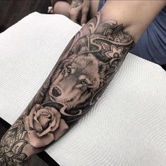 a woman with a wolf tattoo on her arm holding a rose in front of her face