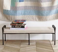 a bench with books on it in front of a quilt