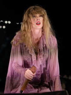 a woman with long blonde hair holding a microphone