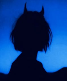 the silhouette of a person with horns on their head is shown in front of a blue background