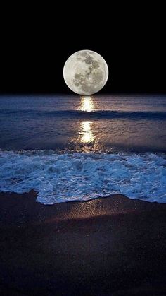 the moon is shining brightly over the water at night on the beach with foamy waves