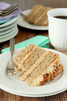 a piece of cake sitting on top of a white plate next to a cup of coffee