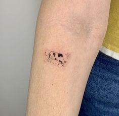 a small cow tattoo on the left arm