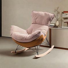 a rocking chair with pink and white checkered fabric on it in a living room