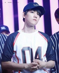 the young man is wearing a baseball uniform and standing in front of an audience with his hands together