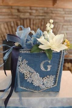 a blue bag with flowers and ribbons on it sitting on top of a white table