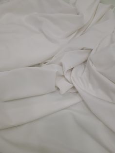 an unmade bed with white sheets and pillows