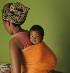 a woman holding a baby wrapped in a towel on top of a bed next to a green wall