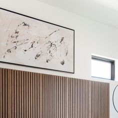 a painting hanging on the wall above a bed in a room with wooden slats