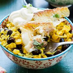 a bowl filled with corn, black beans and sour cream on top of a table