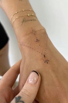 a woman's arm with tattoos on it and her hand holding the other wrist