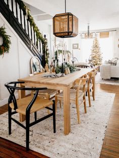 a dining room table and chairs with christmas decorations on the bannister above it