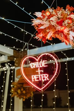 a heart shaped sign hanging from the ceiling with lights strung above it that says choice and peter