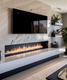 a living room with a large television mounted on the wall and a fire place in front of it