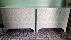 two white dressers sitting next to each other on a tiled floor in front of a green wall