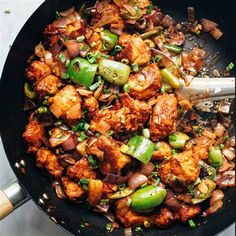 a skillet filled with chicken, peppers and onions