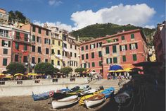 several boats are lined up on the shore in front of buildings with green shutters