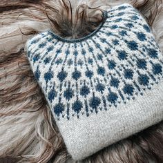 a blue and white knitted hat laying on top of a fur covered animal skin