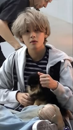 a young boy holding a small dog in his lap