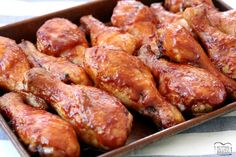 chicken wings covered in bbq sauce in a brown tray on a striped tablecloth