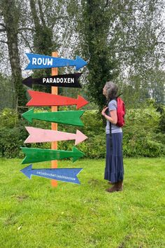 a woman standing in front of a sign pointing to different directions