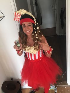 a woman in a red and white dress holding a cell phone with popcorn on it