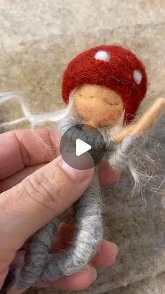 someone is holding a needle doll in their left hand and it looks like they are wearing a red hat