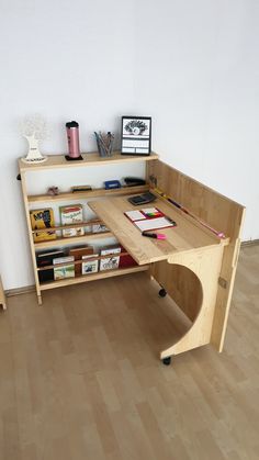 a wooden desk sitting on top of a hard wood floor next to a white wall