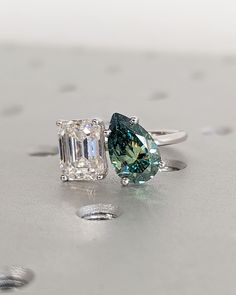 two engagement rings with green and white diamonds