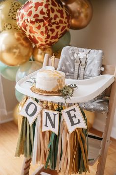 a cake sitting on top of a white plate next to some gold and green balloons